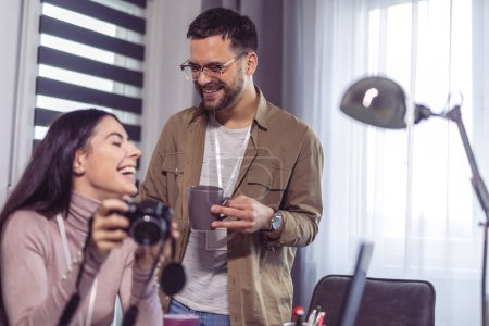 Téléchargez les photos : Jeune couple de photographes travaillant avec un ordinateur portable sur le lieu de travail avec des ordinateurs dans le studio - en image libre de droit
