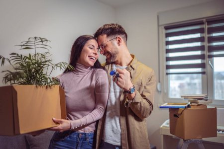 Photo for Smiling couple unpacking boxes in new home.New life.They are showing key of their new house. - Royalty Free Image