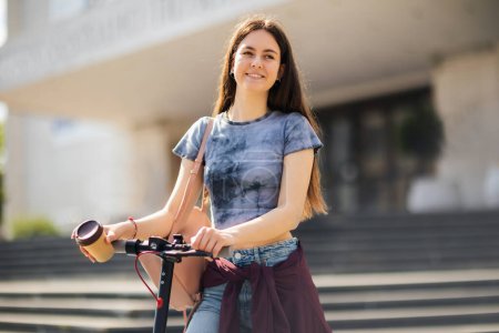 Foto de Estudiante en scooter sosteniendo café al aire libre en el aire libre - Imagen libre de derechos