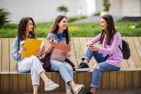 Photo for Group of collage girls sitting on bench and studying for school - Royalty Free Image