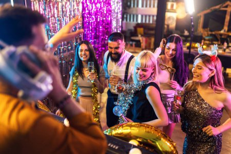 Foto de Dj tocando música de moda en un club nocturno. Gente bailando y festejando. - Imagen libre de derechos