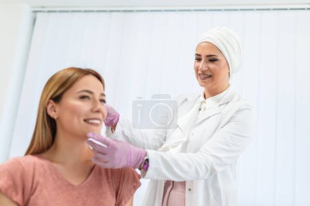 Photo for A doctor examines the patient before the aesthetic procedures. The patient looks at herself and tells her what she wants to change. - Royalty Free Image