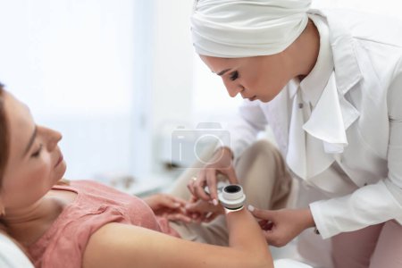 Téléchargez les photos : Le dermatologue examine les taupes ou l'acné du patient avec un dermatoscope. Prévention du mélanome - en image libre de droit