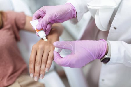 Foto de Médico aplicando crema protectora en las manos del paciente - Imagen libre de derechos
