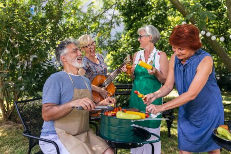 Photo for Elderly people are making barbeque, drinking beverages, making memories, and laughing. - Royalty Free Image