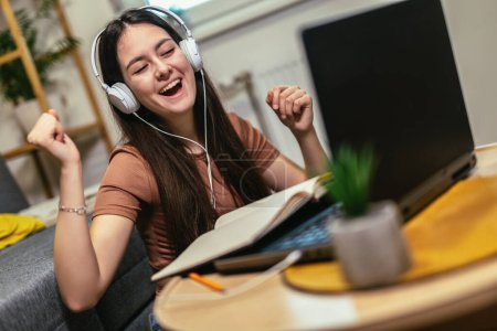 Téléchargez les photos : Teen girl school student wear headphone write notes watch video online webinar learn on laptop - en image libre de droit