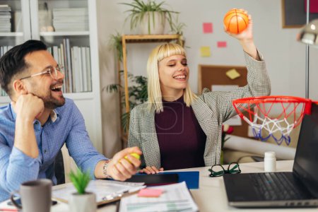 Téléchargez les photos : Portrait de jeunes gens d'affaires travaillant ensemble au bureau à domicile s'amusant avec le basket-ball. Concept de démarrage du travail d'équipe en couple - en image libre de droit