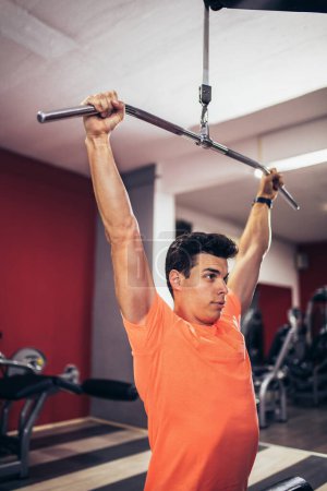 Foto de Joven hombre guapo haciendo ejercicios en el gimnasio - Imagen libre de derechos