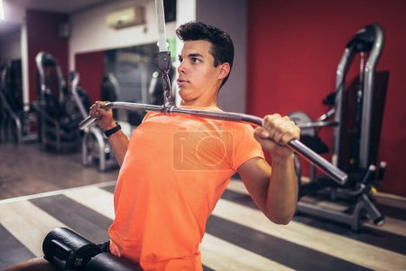 Téléchargez les photos : Jeune homme beau faire des exercices dans la salle de gym - en image libre de droit