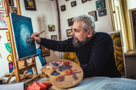 Photo for Mature man painting on canvas in art studio. - Royalty Free Image