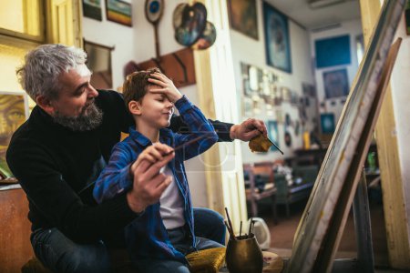 Téléchargez les photos : Père et fils travaillent et peignent ensemble dans un atelier d'art - en image libre de droit