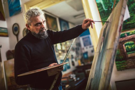 Téléchargez les photos : Mature homme peinture sur toile en atelier d'art
. - en image libre de droit