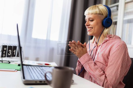 Téléchargez les photos : Jeune femme blonde parler à quelqu'un en ligne sur son ordinateur portable - en image libre de droit