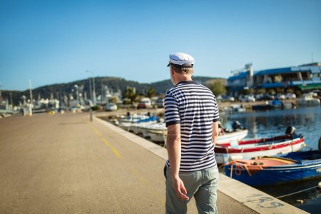 Photo for Mature man standing near the sea dressed in a sailor's shirt and hat. - Royalty Free Image
