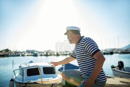 Photo for Mature man standing near the sea dressed in a sailor's shirt and hat. - Royalty Free Image