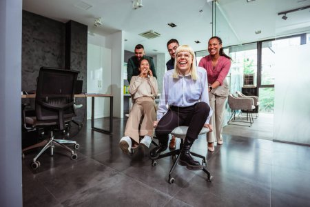 Photo for Group of professional people racing with the chairs while on a break in the modern office - Royalty Free Image