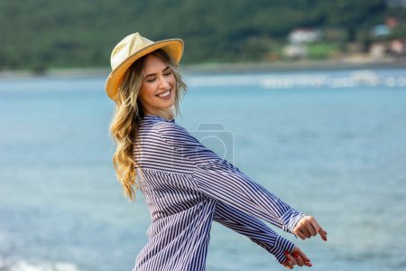 Téléchargez les photos : Joyeux jeune belle femme marchant seule sur la plage - en image libre de droit