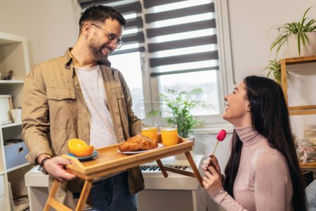 Foto de Hombre sosteniendo bandeja de desayuno a una mujer relajada feliz - Imagen libre de derechos