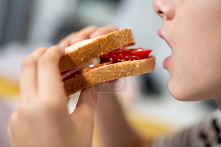 Téléchargez les photos : Le gamin mange un sandwich fait maison à la maison - en image libre de droit