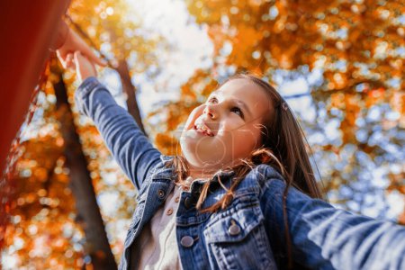 Photo for Little girl having fun at the colorful park on a sunny fall day. - Royalty Free Image