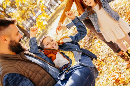 Photo for Parents tickle their children. Sunny autumn day in the colorful park - Royalty Free Image