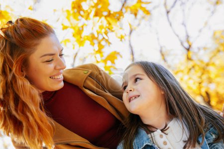 Photo for Ginger mom having fun with her daughter in the colorful park. Autumn day. - Royalty Free Image