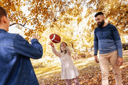 Téléchargez les photos : Famille jouant au football américain dans le parc. Famille et enfants, concept nature. - en image libre de droit