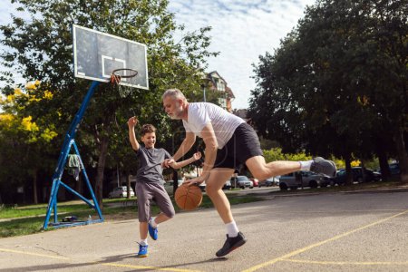 Foto de Hombre maduro jugando baloncesto con su hijo - Imagen libre de derechos