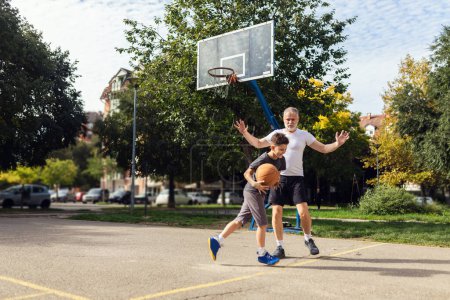 Téléchargez les photos : Homme mûr jouant au basket avec son fils - en image libre de droit