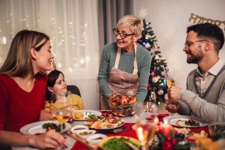Téléchargez les photos : Bonne famille multi-générations profiter d'un déjeuner ensemble à la maison. Famille le dîner de Noël à la maison - en image libre de droit