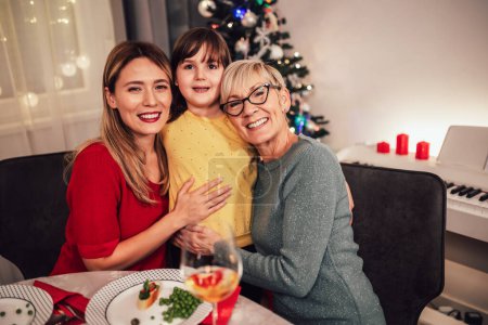 Foto de Madre, hija y nieta vinculándose en la cena de Navidad familiar - Imagen libre de derechos