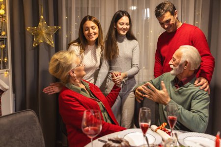 Foto de Familia feliz hablando junto a la mesa de comedor en la Nochebuena. - Imagen libre de derechos