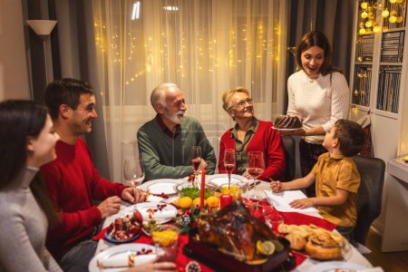 Photo for Mother brought tasty cake on the dining table. Family celebrating Christmas. - Royalty Free Image