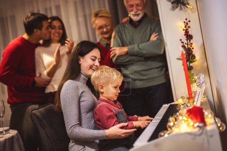 Foto de Nieta y nieto tocando un piano para su familia en Nochebuena. - Imagen libre de derechos