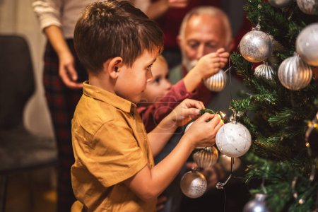 Téléchargez les photos : Famille décorer ensemble un arbre avec des lumières et des balles. Temps de Noël. - en image libre de droit
