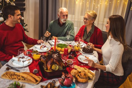 Photo for Happy family having Vhristmas dinner with their grandparents. Eating homemade food, drinking beverages. Home is decorated for New Year's Eve and Christmas - Royalty Free Image