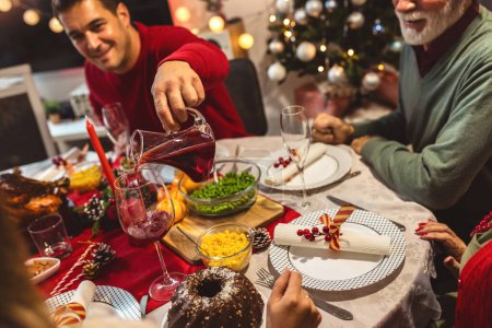 Téléchargez les photos : Joyeux repas de famille à Vhristmas avec leurs grands-parents. Manger des aliments maison, boire des boissons. La maison est décorée pour la Saint-Sylvestre et Noël - en image libre de droit