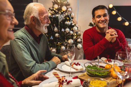 Foto de Familia feliz cenando Vhristmas con sus abuelos. Comer comida casera, beber bebidas. Casa está decorada para la víspera de Año Nuevo y Navidad - Imagen libre de derechos