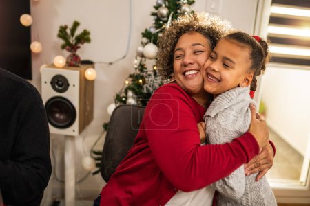 Téléchargez les photos : Grand-mère étreignant avec sa petite-fille la veille de Noël - en image libre de droit