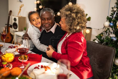 Téléchargez les photos : Les grands-parents embrassant leur petite-fille la veille de Noël. - en image libre de droit