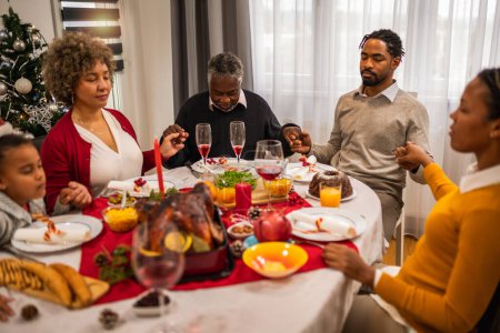 Téléchargez les photos : Prier en famille avant de manger un délicieux dîner de Noël. - en image libre de droit