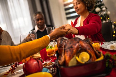 Téléchargez les photos : Prier en famille avant de manger un délicieux dîner de Noël. - en image libre de droit