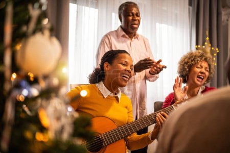 Foto de Familia afroamericana tocando la guitarra y cantando en Nochebuena. - Imagen libre de derechos