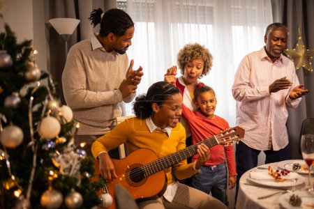 Photo for African American family playing guitar and singing  on Christmas Eve. - Royalty Free Image