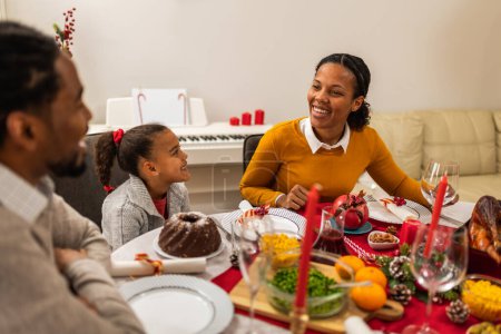 Téléchargez les photos : Les parents se lient avec leur fille lors d'un dîner de Noël. - en image libre de droit