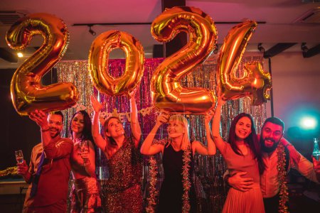 Photo for Group of younge people celebrating New Year at the nightclub. They are holding gold number ballons - Royalty Free Image