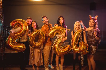 Téléchargez les photos : Groupe de jeunes célébrant le Nouvel An à la boîte de nuit. Ils détiennent nombre d'or ballons - en image libre de droit
