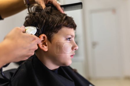 Photo for Cute young boy getting a haircut by hairdresser - Royalty Free Image