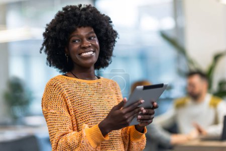 Téléchargez les photos : Femme d'affaires debout dans son bureau avec sa tablette. - en image libre de droit