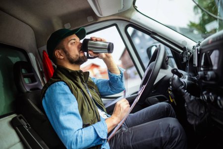 Photo for Young handsome man working in towing service and drinking coffee so he could get some energy - Royalty Free Image